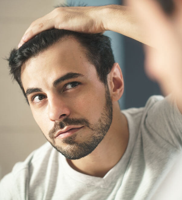 Dark haired male admiring his hair restoration