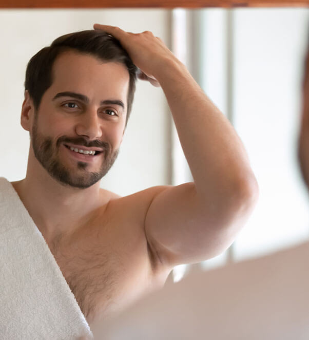 Man looking in the mirror admiring his hair restoration
