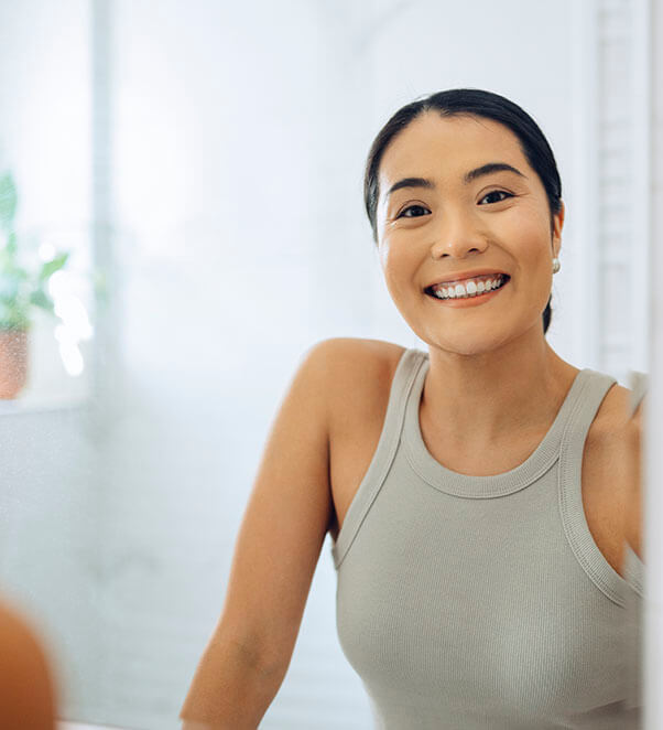Asian woman admiring her great skin in a mirror